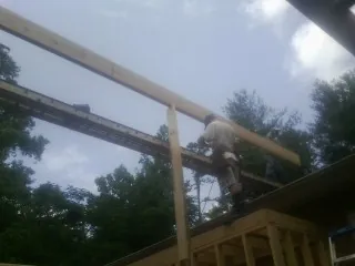 Carpenter setting a ridge beam over a new addition frame — Ice Dam Removal by Roofing Brothers in Coburn