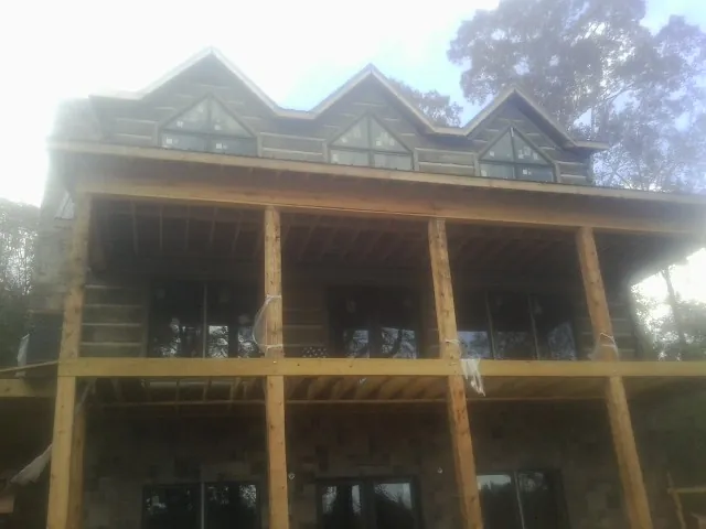 Dormers and porch framing on a large log home under construction — Roof Coating work by our crew in Coburn