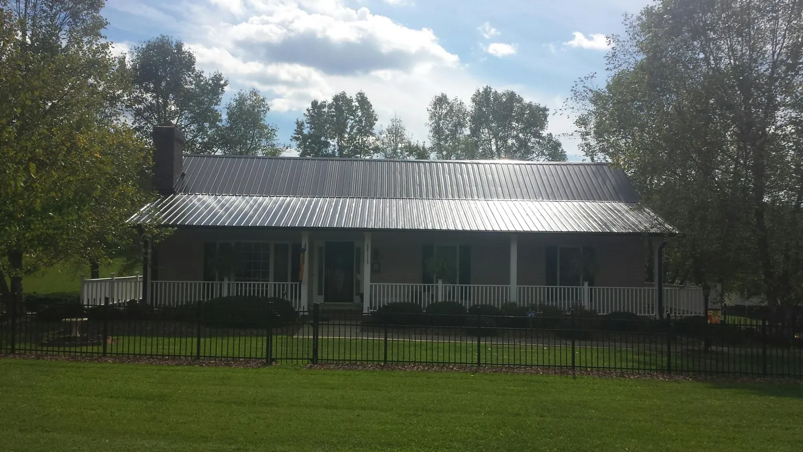 Gray metal roof on a brick ranch with a full width front porch — Gutter Guard Installation work by our crew in Coburn