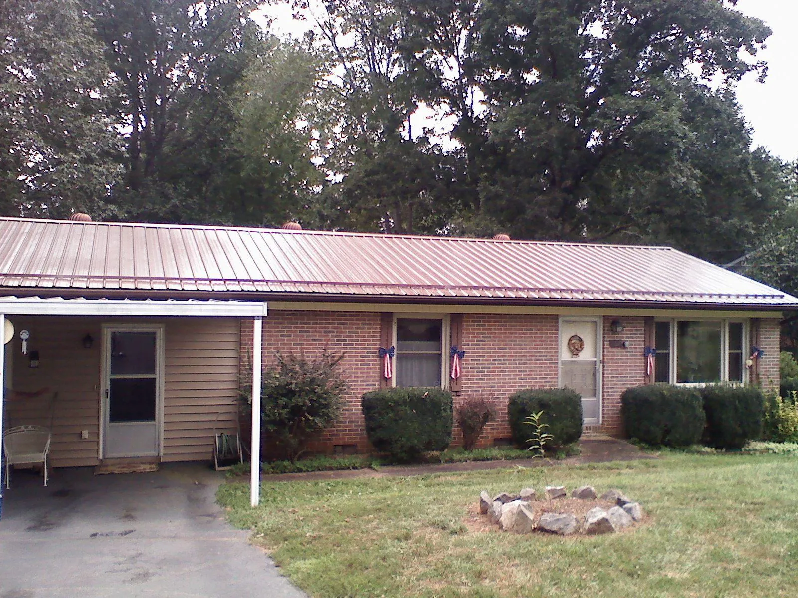 Bronze metal roof and carport on a brick ranch home — Roof Repair work by our crew in Coburn